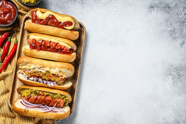 Hot dogs fully loaded with assorted toppings on a tray