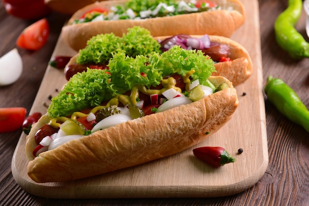 Photo hot dogs and vegetables on wooden cutting board