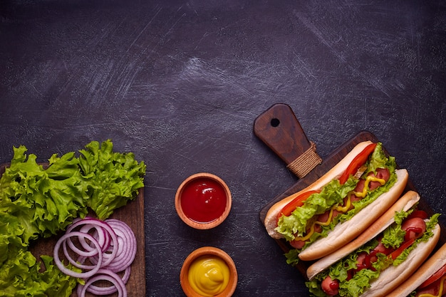 Hot dogs with sausage, fried onion, coriander leaves, cheese sauce and mustard . Fast food. Top view, copy space