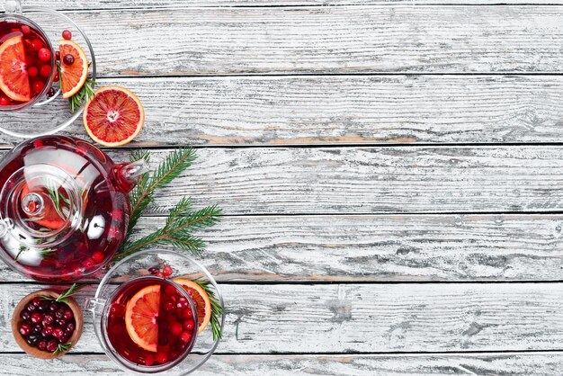 Hot drink of cranberry and orange in cups On a white wooden background Top view Free space for your text