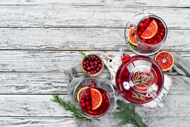 Hot drink of cranberry, and orange, in cups. On a white wooden background. Top view. Free space for your text.