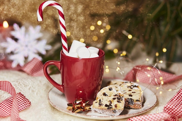 Hot drink in red cup with marshmallow and Christmas stollen traditional holidays bread gingerbread cookies candy cone stick Festive holidays Christmas background Christmas food Merry tradition