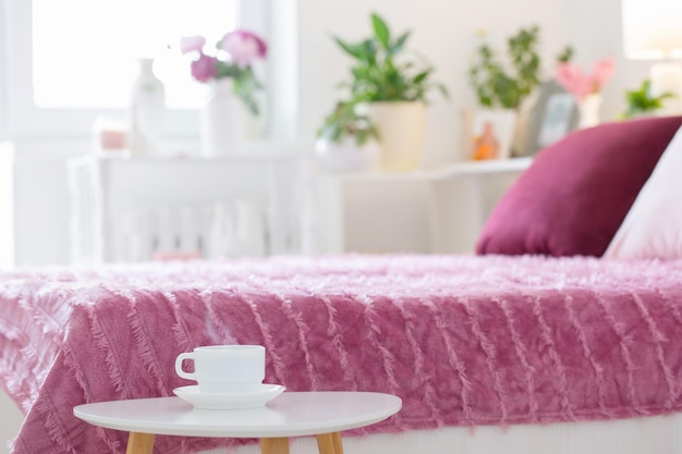 Hot drink in white cup on background pink and white bedroom