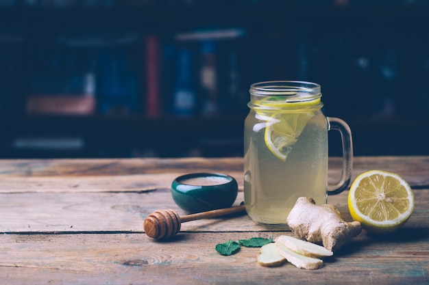 Hot drink with honey, lemon and ginger on wooden background