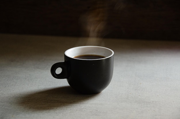 Foto espresso caldo in una tazza nera su sfondo grigio