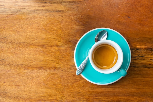 Hot espresso in blue cup on wooden table. Favorite caffeine beverage.