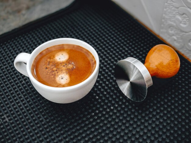 Photo hot espresso cup and coffee tamper