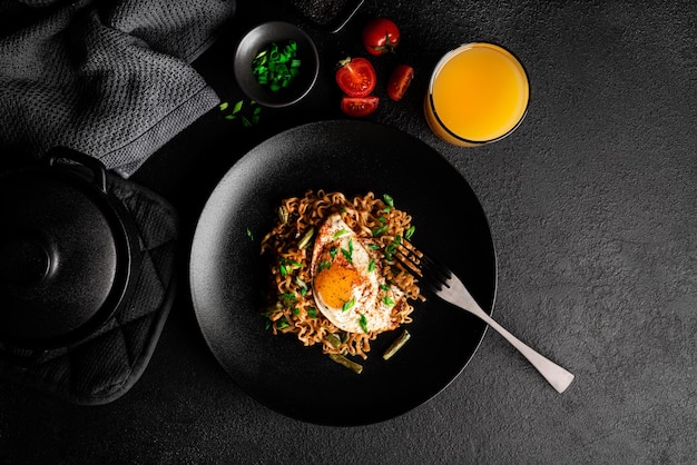 Hot fresh noodles with fried egg dark background. High quality photo