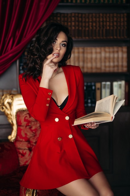책을 손에 들고 그녀의 입술을 만지고 빨간 드레스에 뜨거운 여자