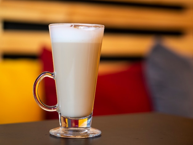 Hot Glass cup of coffee latte on wooden table in a cozy warm interior