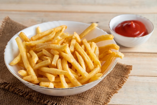 Hot golden french fries with ketchup on a wooden background Tasty american fast food