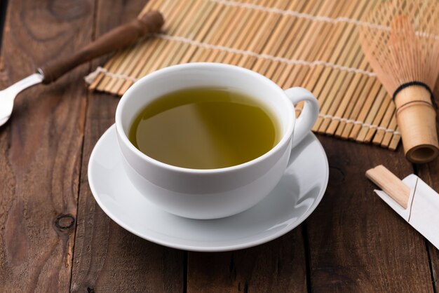 Tè verde caldo in tazza su legno