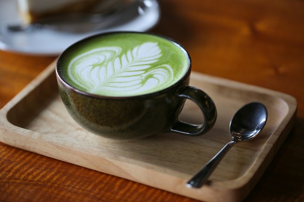 Hot green tea matcha latte in cup on table.