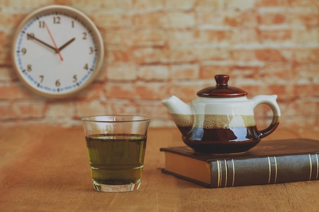 Горячий зеленый чай с небольшим чайником на деревянный стол.