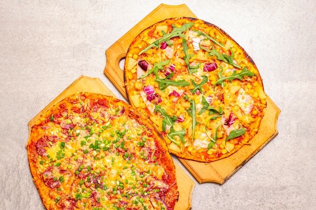 Photo hot homemade hawaiian and salami pizza on wooden board on stone surface .