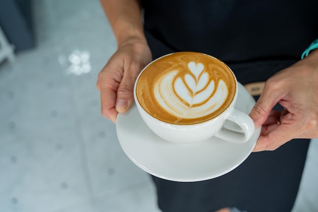 手テーブルのホットラテアートコーヒーリラックスタイム