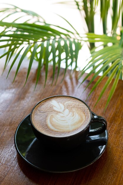 木のテーブルの上の熱いラテアートコーヒーは時間をリラックスします