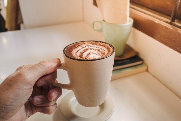 朝、テーブルの上に白いマグカップで出されるホットラテコーヒー