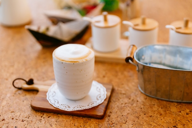 Hot Latte served in ceramic cup on wooden plate. Smooth white and brown froth.