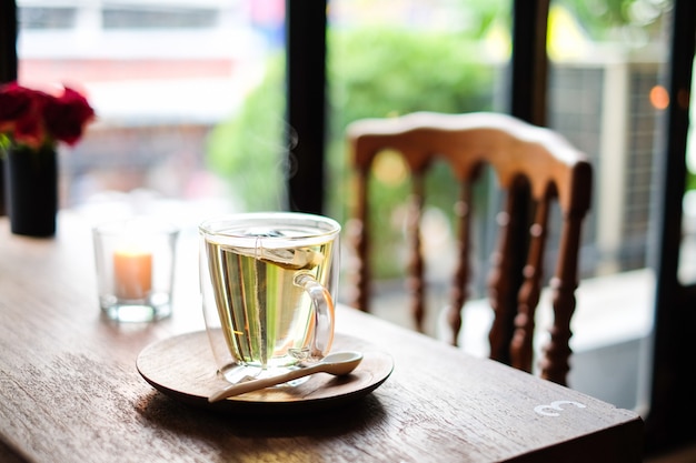 Il tè caldo alla lavanda in vetro serve con un cucchiaio di legno e un piattino