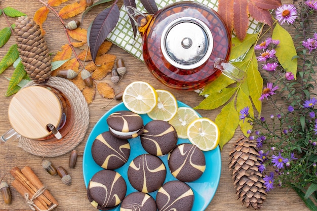 Hot lemon tea and cookies with cream frosting on a wooden table top view