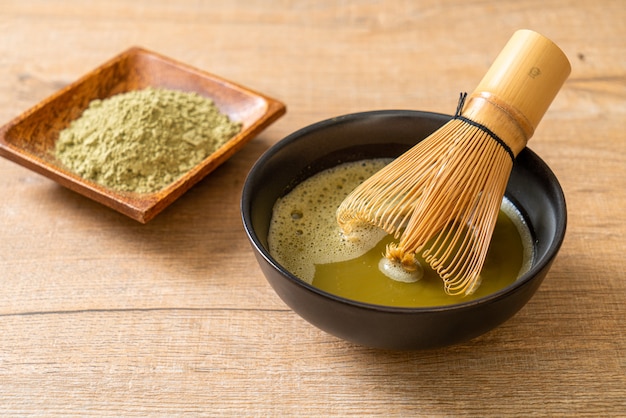 hot matcha green tea cup with green tea powder and whisk