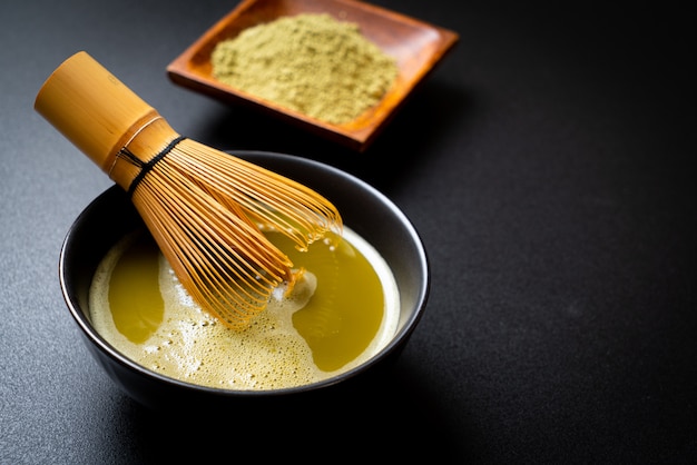 hot matcha green tea cup with green tea powder and whisk