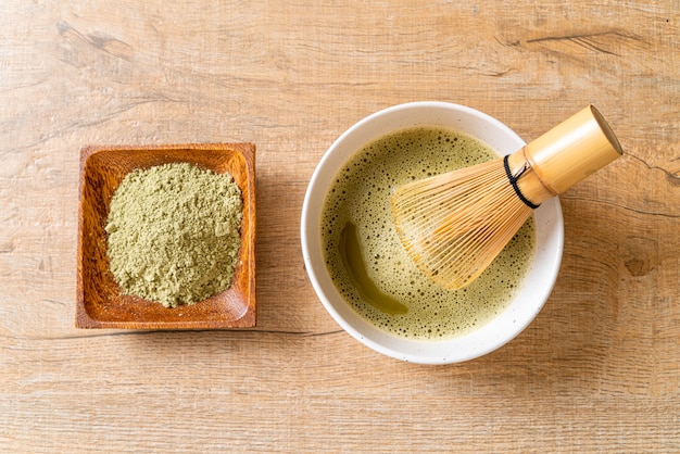 hot matcha green tea cup with green tea powder and whisk