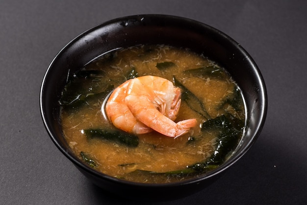 Hot miso soup with shrimp in bowl on black background Japanese food