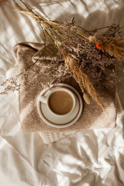 Hot mug of cappuccino on wooden tray on the bed breakfast bouquet of dried flowers Spring scenery Cozy house Beige natural colors