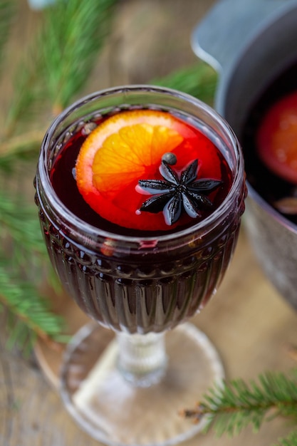 Hot mulled wine in a glass. Beautiful Christmas drink. Hot autumn mulled wine on a wooden table. Delicious wine and fruit drink. 