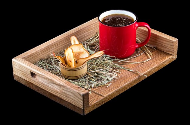 Hot mulled wine with a metal mug on a wooden board with straw and apple chips