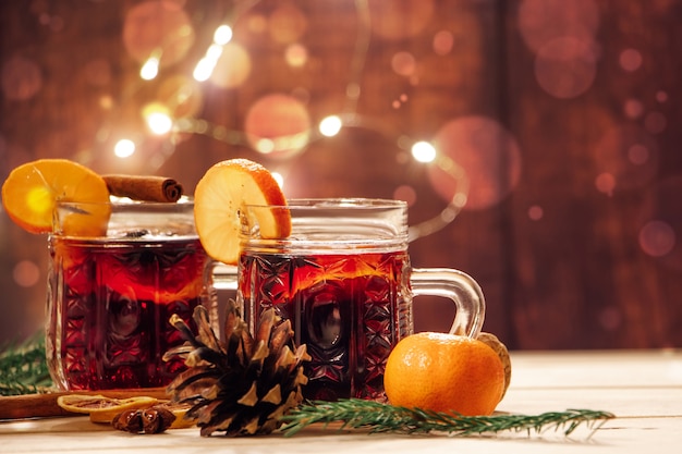 Hot mulled wine with spices in glass cup on a wooden background. Traditional Christmas warming drink.