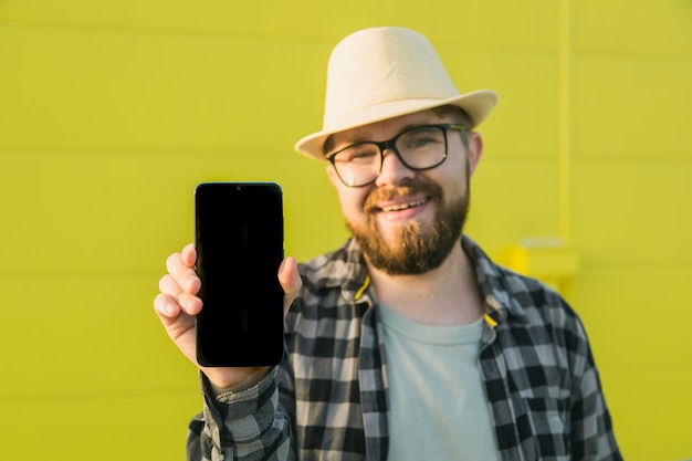Горячее предложение счастливый парень держит мобильный телефон с черным пространством для копирования и улыбается человеческие эмоции на лице и место для рекламы и текста