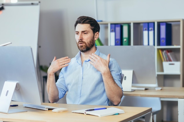 Hot in the office a businessman in a shirt working in a bright modern office waving his arms trying to freshen up