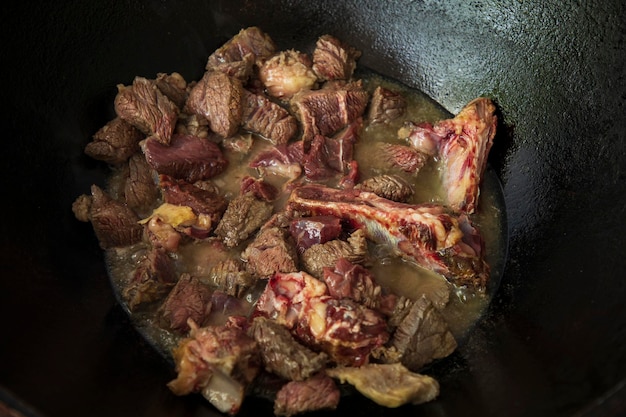 a hot oil and raw meat in a pan cooking slowly