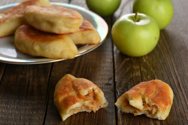 Hot patty with fresh green apples on wood background