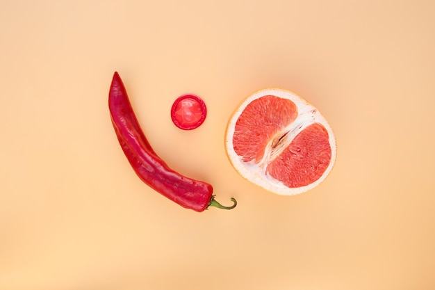 Hot pepper, grapefruit, condoms on beige background. Concept of sex education. Flat lay. Top view. Space for text.