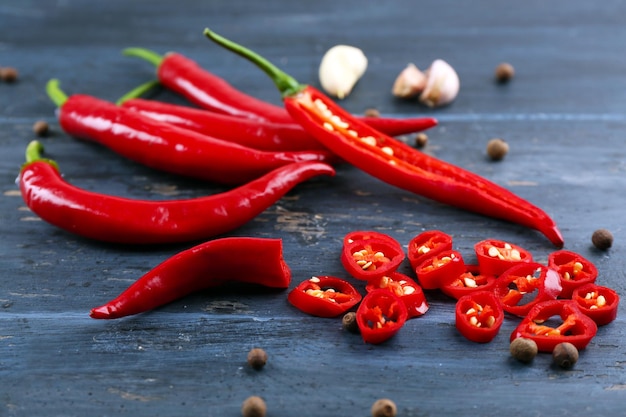 Hot peppers with spices on wooden table close up