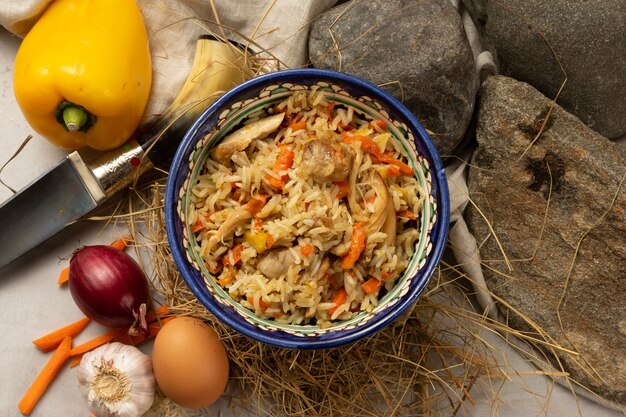 Hot pilaf with chicken fillet in a decorative Uzbek national bowl with a traditional pattern. A classic oriental dish made of boiled rice, meat and vegetables with spicy spices