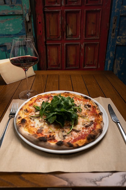 Hot pizza and a glass of red wine on wooden background