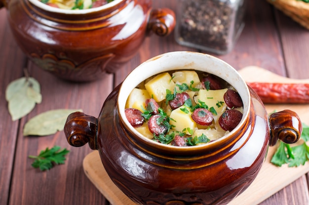 Hot potato goulash with bacon and sausages served in a ceramic bowl