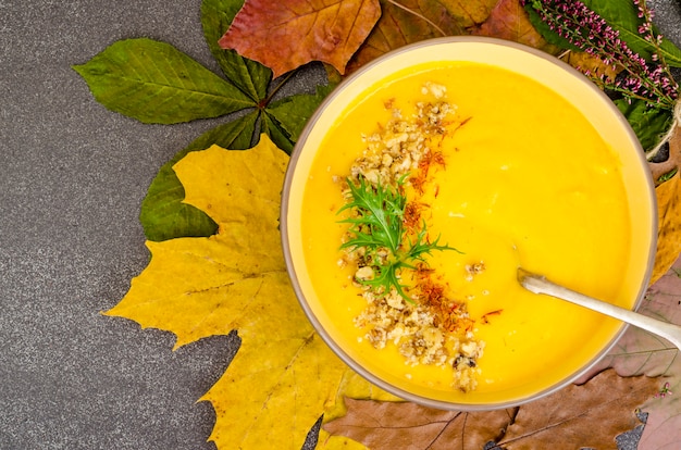 Hot pumpkin soup on dried autumn leaves.