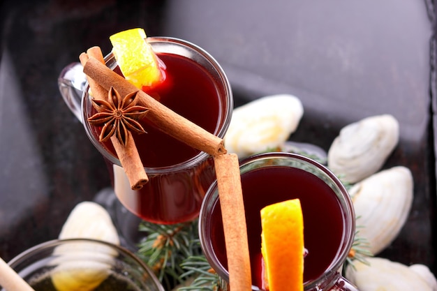 Hot red mulled wine bee honey slices of oranges and spices on a dark background Christmas decoration with spruce branches Closeup