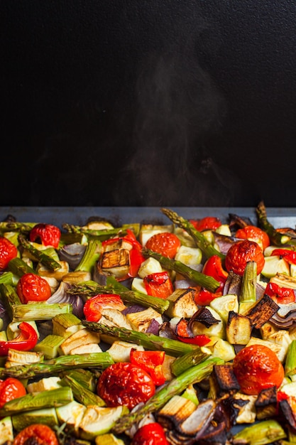 Foto verdure arrostite calde in forno fette miste pomodori asparagi zucca cipolla e olio d'oliva in una teglia concetto di dieta sana