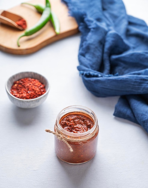 Hot sauce adjika Homemade appetizer with pepper and tomatoes in a jar on light background The concept of Caucasian and Georgian food