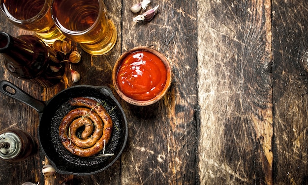 Hot sausages with cold beer on wooden table.