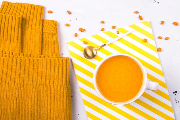 Hot sea buckthorn fruit tea with a warm knitted sweater. Fall season