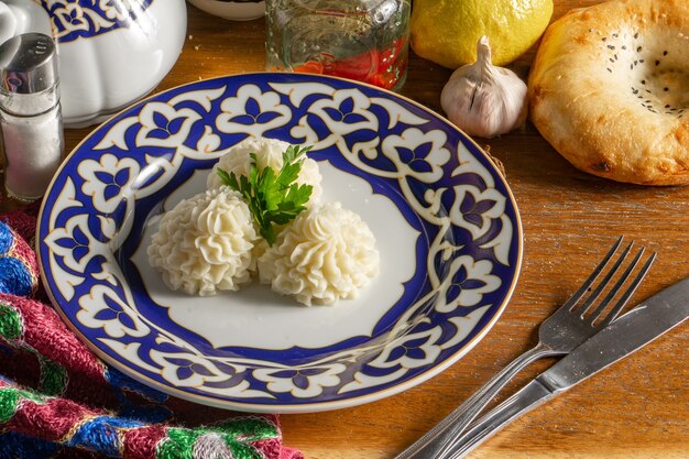 Hot side dish of mashed potatoes in the shape of a flower decorated with parsley in a plate with a traditional Uzbek pattern