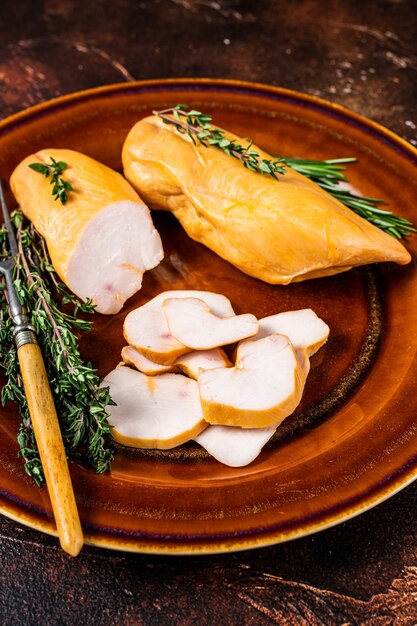 Hot Smoked chicken breast Poultry meat in a rustic plate with herbs